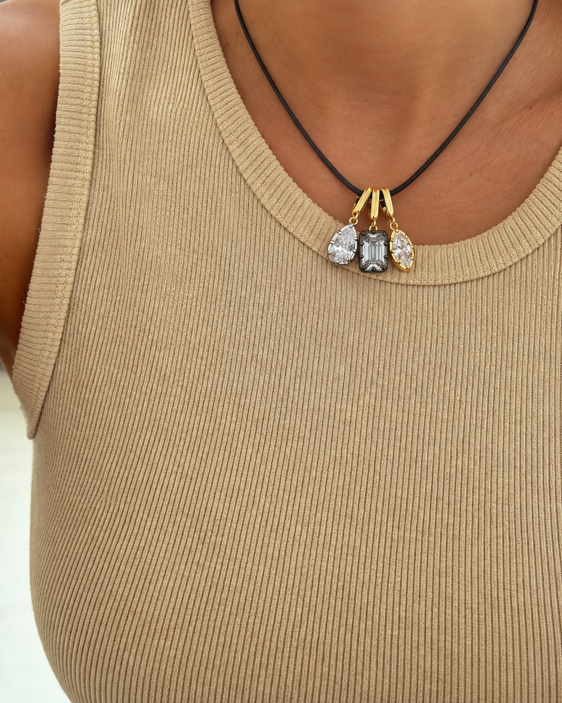 Three interchangeable Vittoria charms styled on a black cord necklace