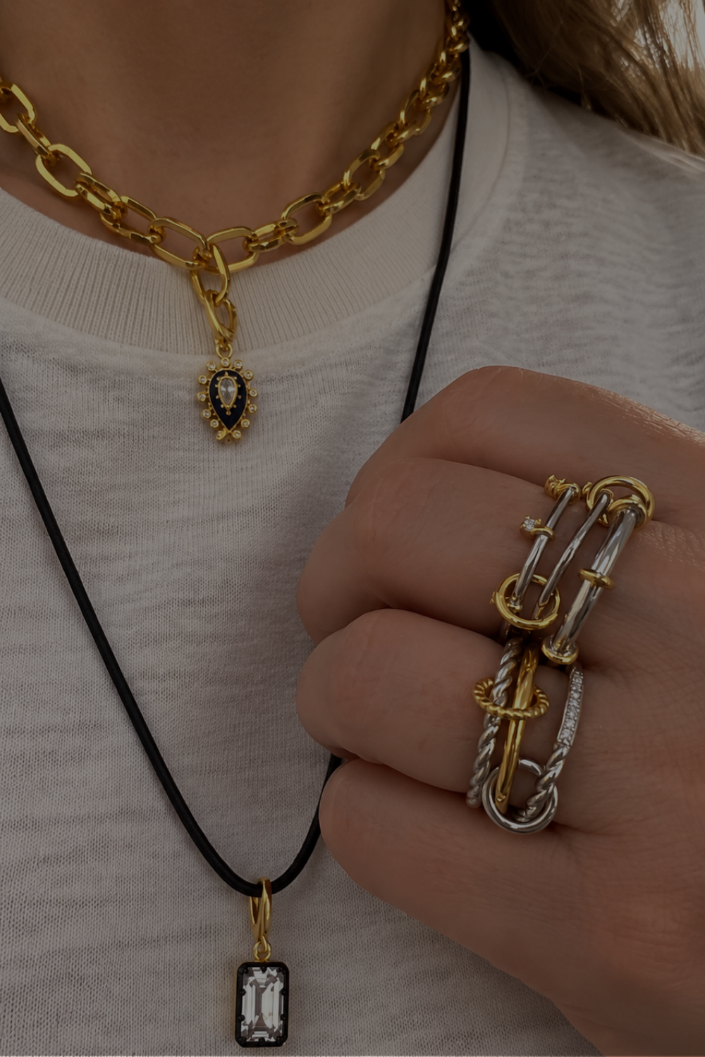 Dimitra’s everyday jewellery look by Galleria Armadoro featuring a black cord with Vittoria emerald-cut charm, layered Cara chain with evil eye charm and mixed-metal statement rings.