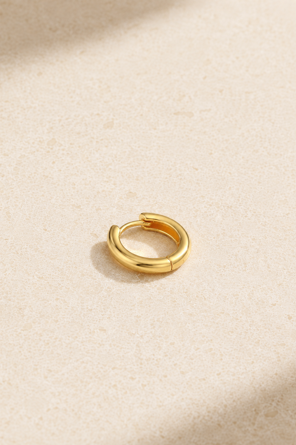 Small gold cartilage huggie earring standing upright, ideal for upper lobe and helix piercings