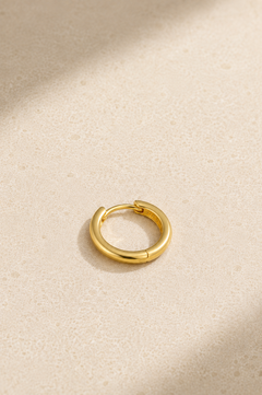 Small gold huggie hoop earring lying flat, ideal for everyday ear stacks and cartilage piercings
