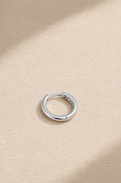 Small silver huggie hoop earring lying flat, ideal for everyday ear stacks and cartilage piercings