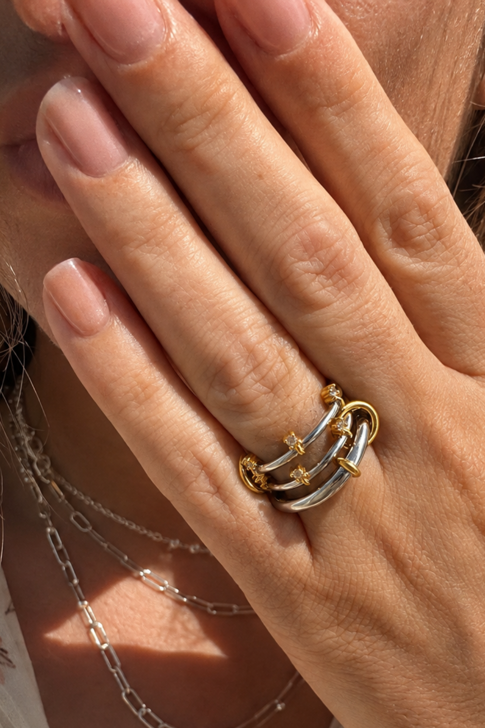 Galleria Armadoro Clara Ring in mixed metals, worn in warm sunlight with silver paperclip chains layered in the background at 40 cm and 45 cm.