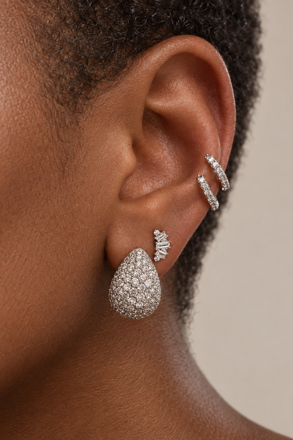 Silver ear stack by Galleria Armadoro featuring the Abraccio earring at the lobe, a crystal stud and double helix hoops.