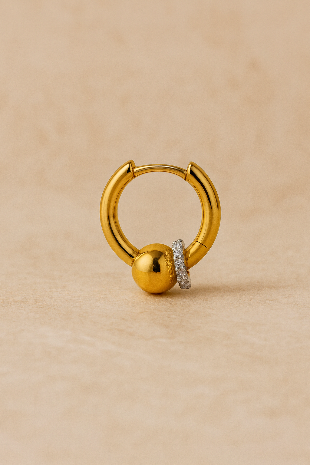 Angled macro of Kora gold huggie with polished bead and CZ ring