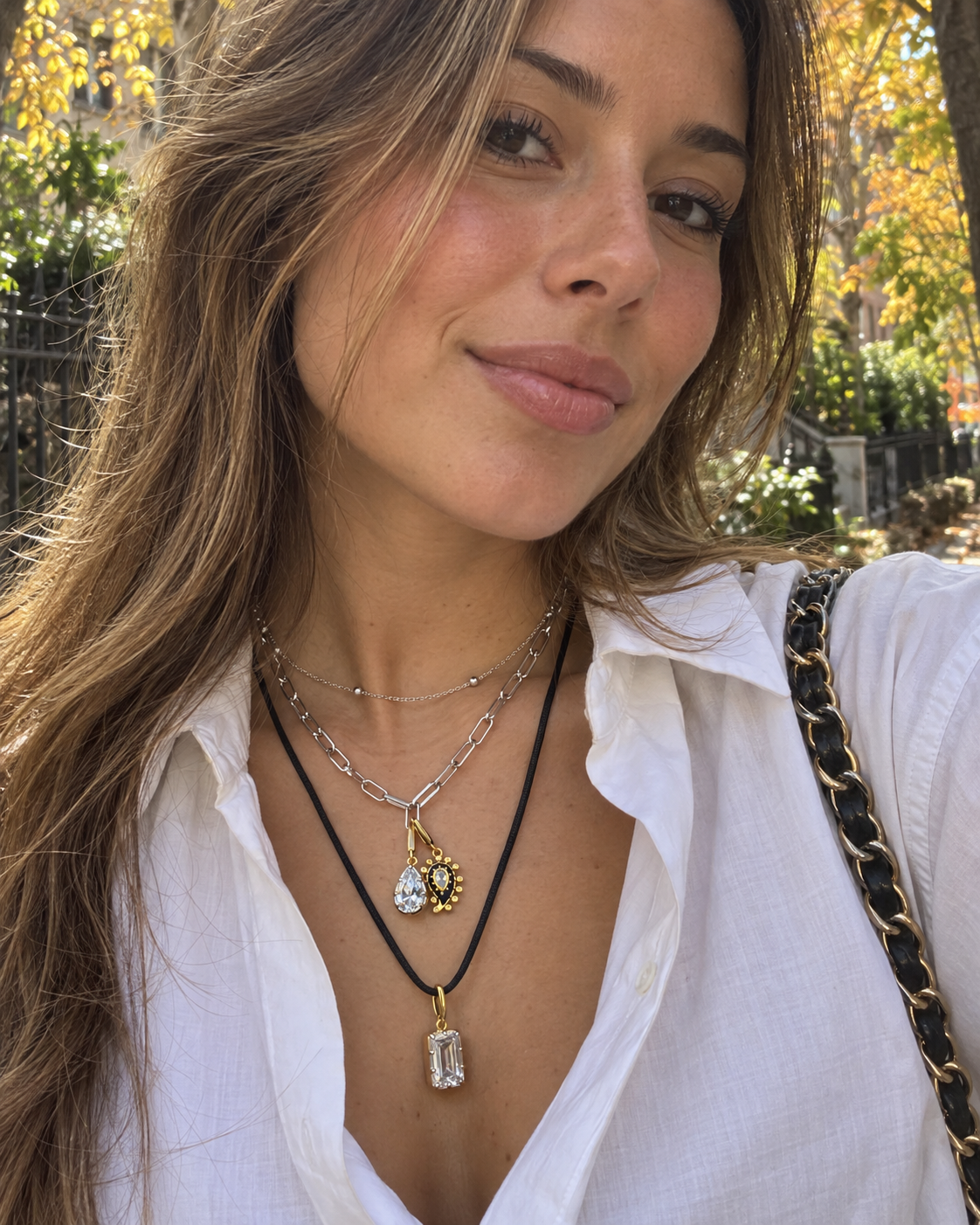 Mixed-metal layered necklace look by Galleria Armadoro featuring silver chains, a gold evil-eye charm, teardrop charm and black cord with Vittoria black-rhodium charm.