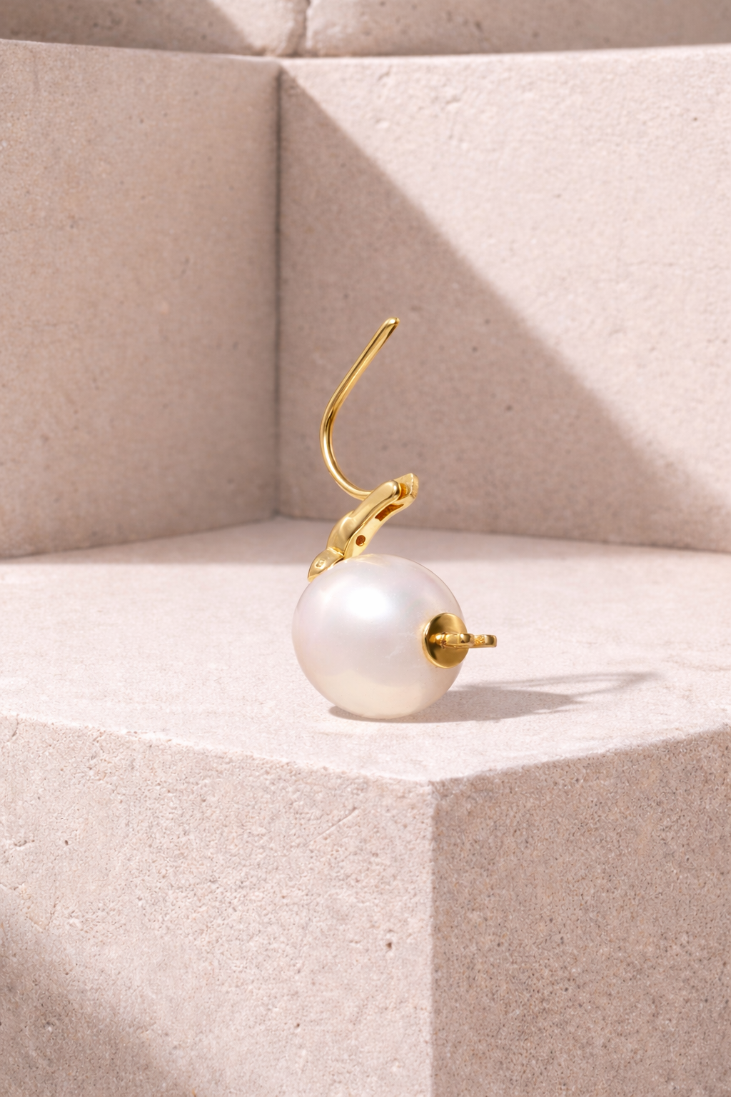 Back view of Tasha Pearl gold vermeil mini hoop earring showing open hinge and 11mm white pearl on stone background