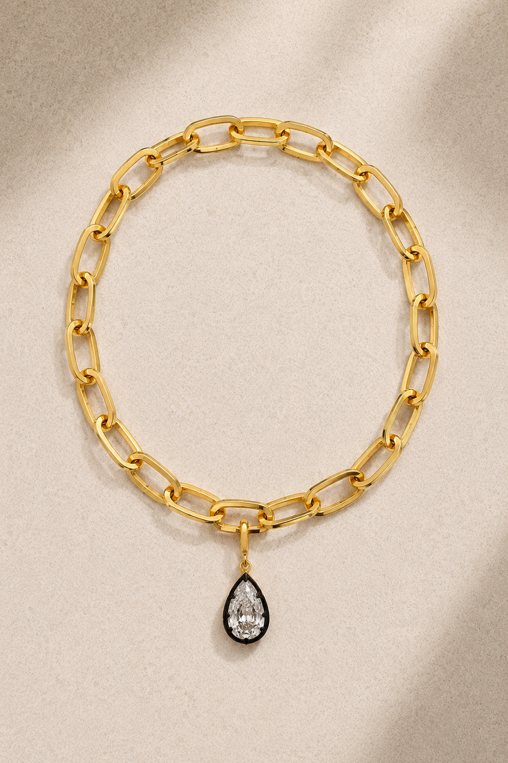 Cara chunky gold bracelet with Vittoria black rhodium crystal charm on beige background
