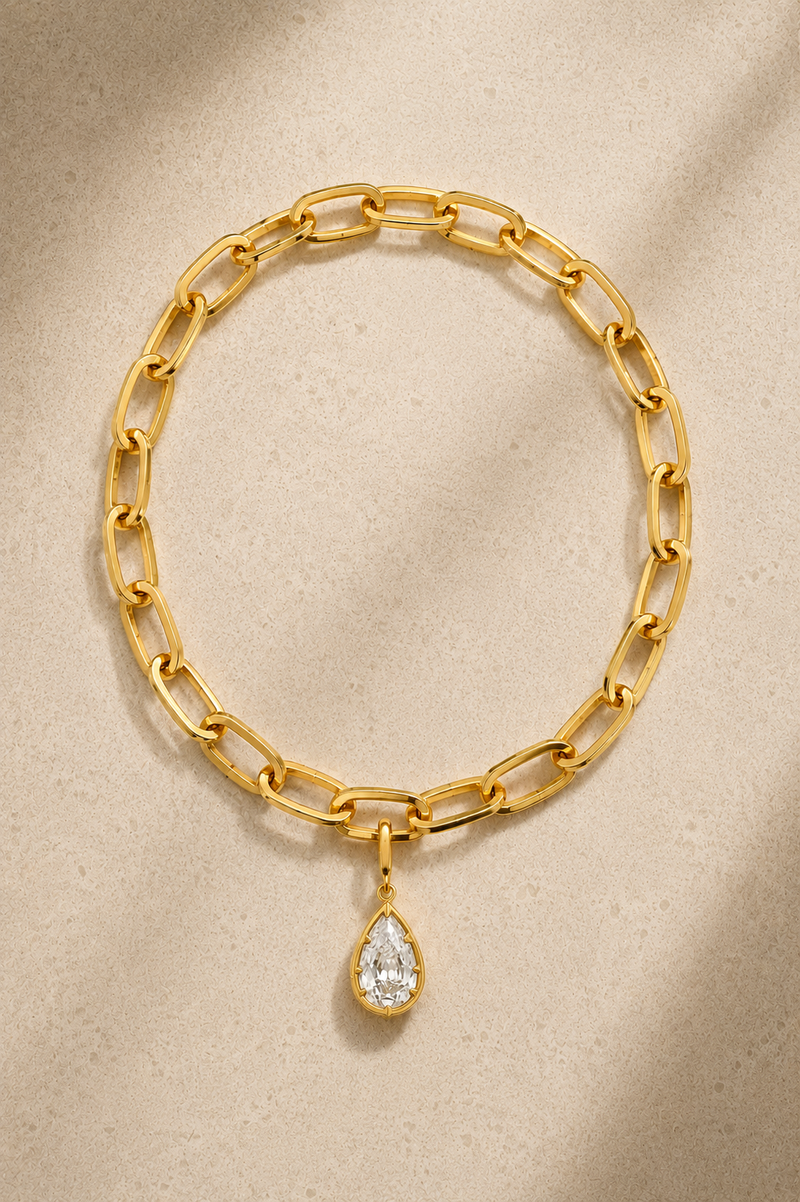 Cara chunky gold bracelet with Vittoria gold crystal charm on beige background