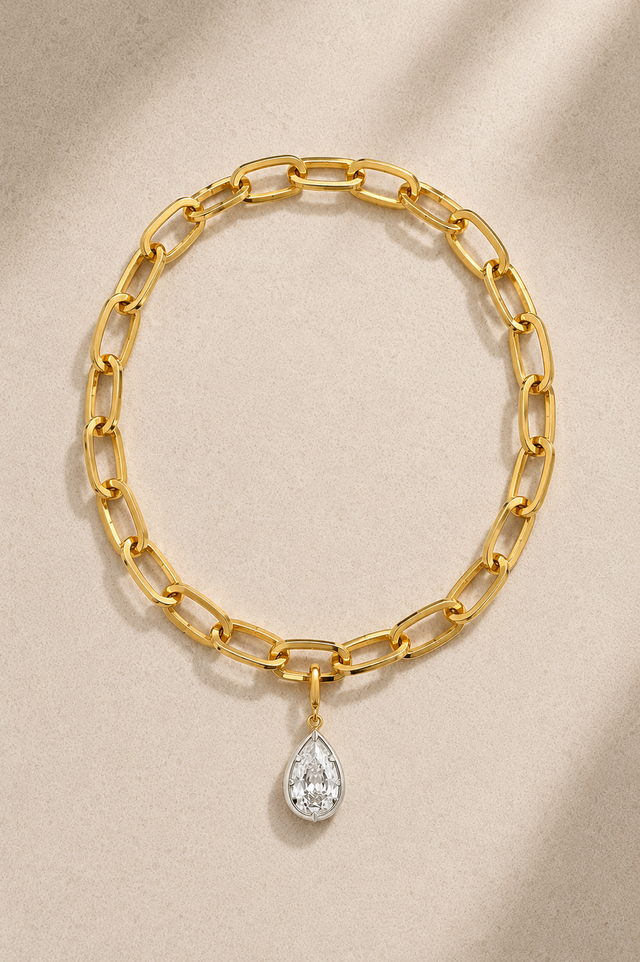 Cara chunky gold bracelet with mixed-metal Vittoria crystal charm on beige background