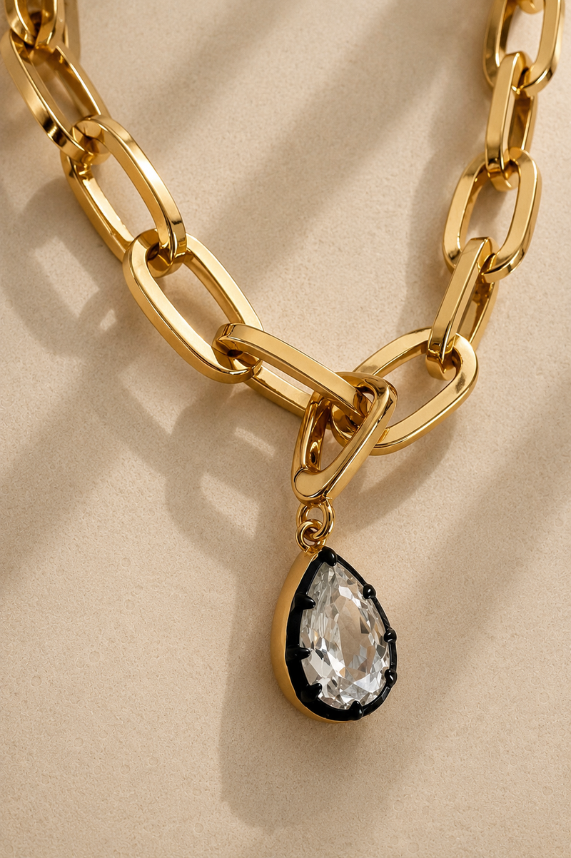 Cara chunky gold paperclip chain necklace with Vittoria black rhodium crystal charm on beige background