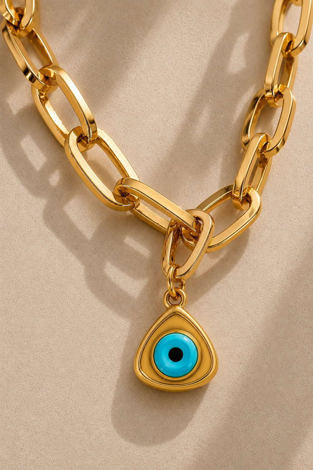Close-up of oversized gold paperclip chain with turquoise triangle evil eye charm