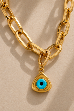 Close-up of oversized gold paperclip chain with turquoise triangle evil eye charm