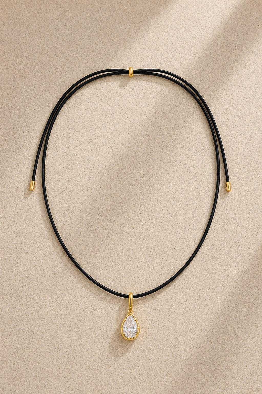 Close-up of Vittoria gold teardrop crystal charm hanging on adjustable black cord necklace