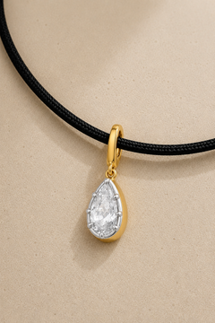 Close-up of silver and gold Vittoria crystal charm hanging on adjustable black cord necklace