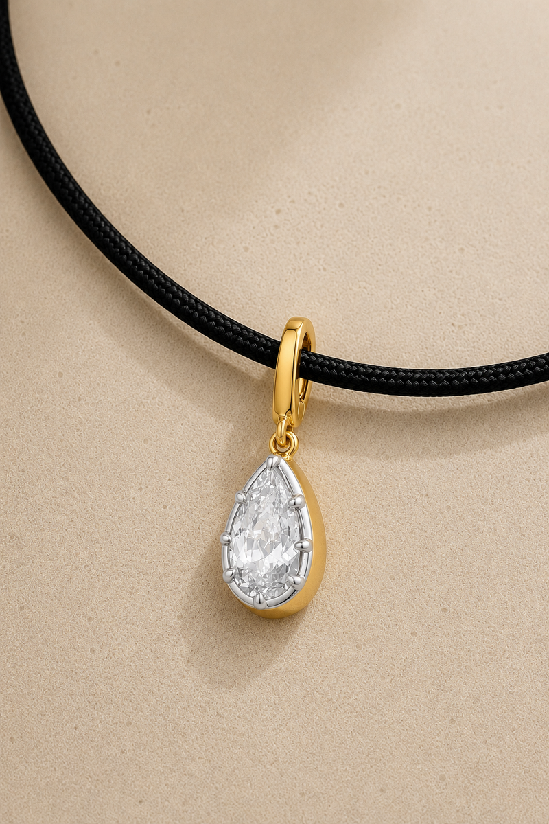 Close-up of silver and gold Vittoria crystal charm hanging on adjustable black cord necklace