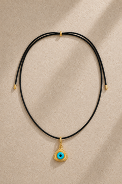 Black adjustable cord necklace with triangle evil eye charm on beige background
