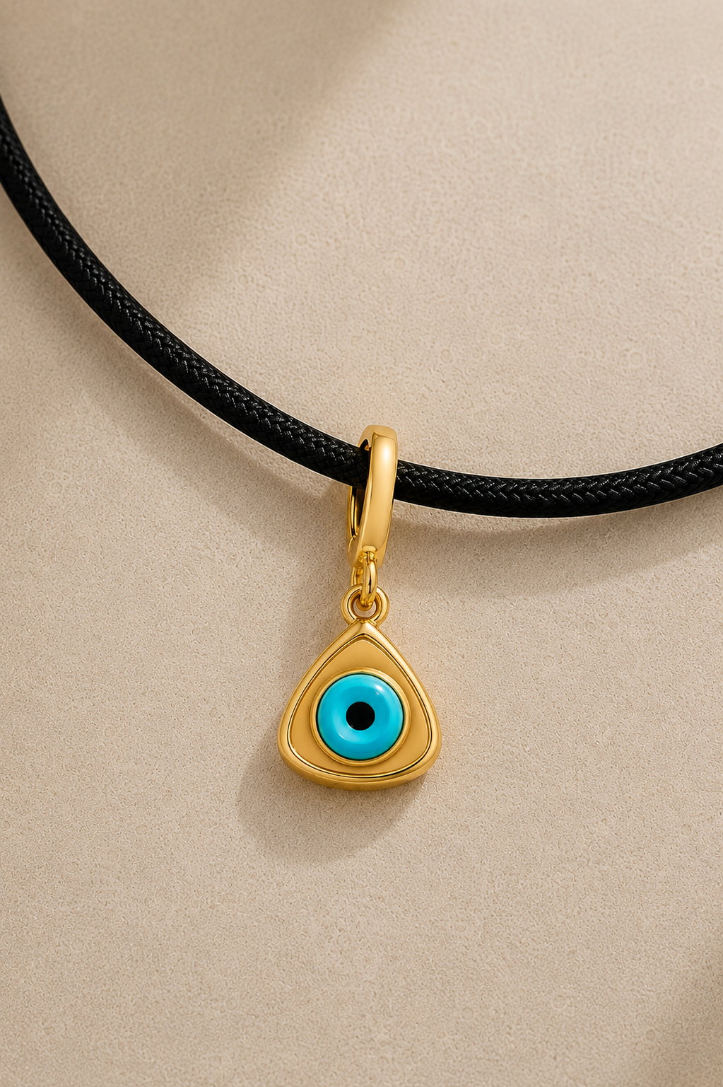 Close-up of turquoise triangle evil eye charm hanging on adjustable black cord necklace