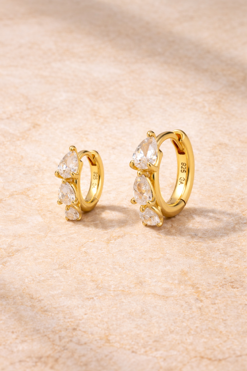 Double ear piercing gold huggie set with 6.5mm and 8.5mm cascade graduated pear cut cubic zirconia