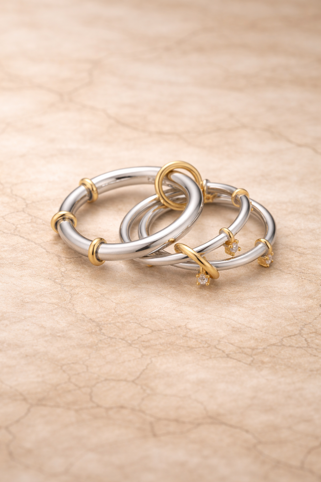 Clara two-tone linked ring in silver and gold tones on neutral stone background