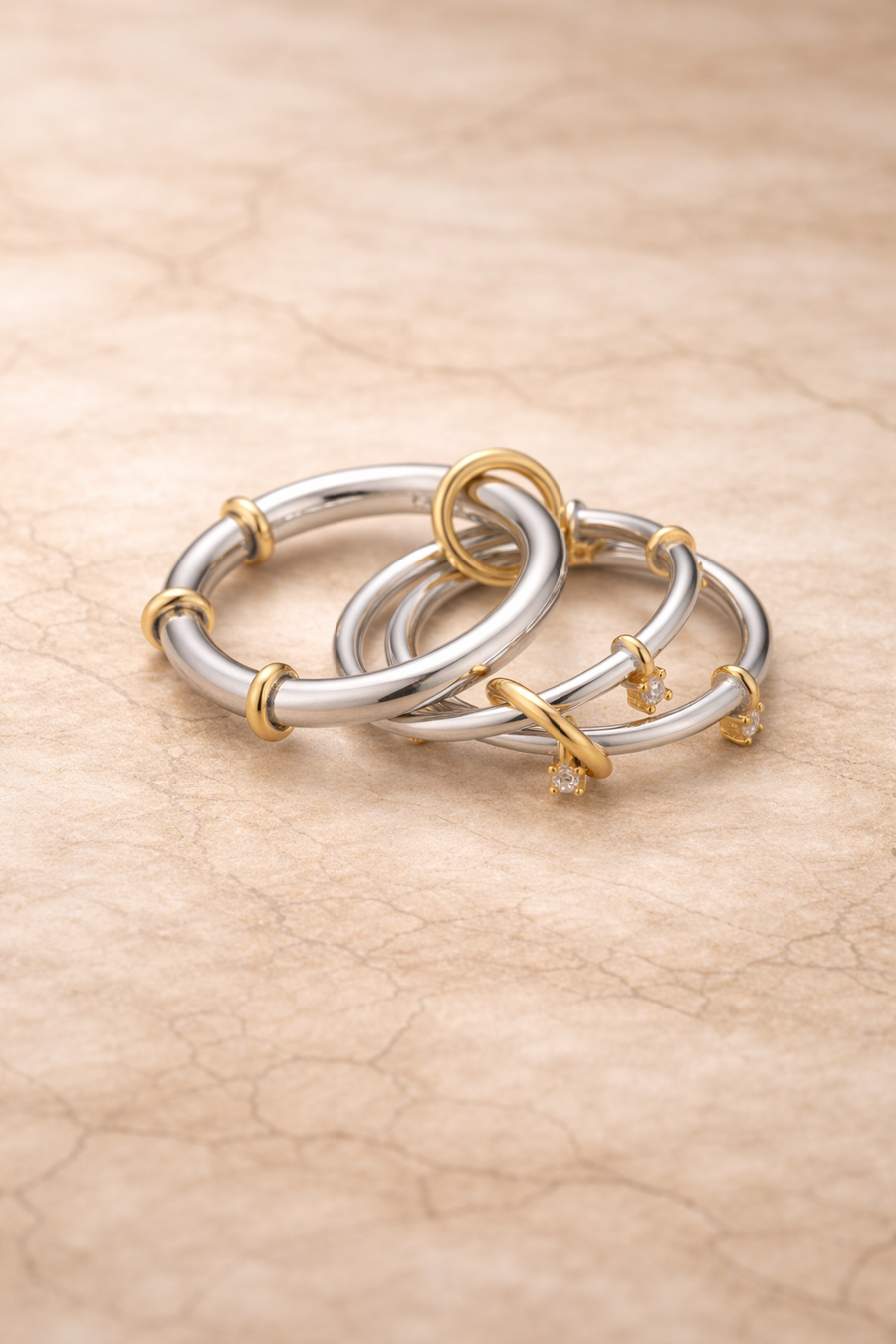 Clara two-tone multi-band ring in silver and gold tones on a neutral stone background