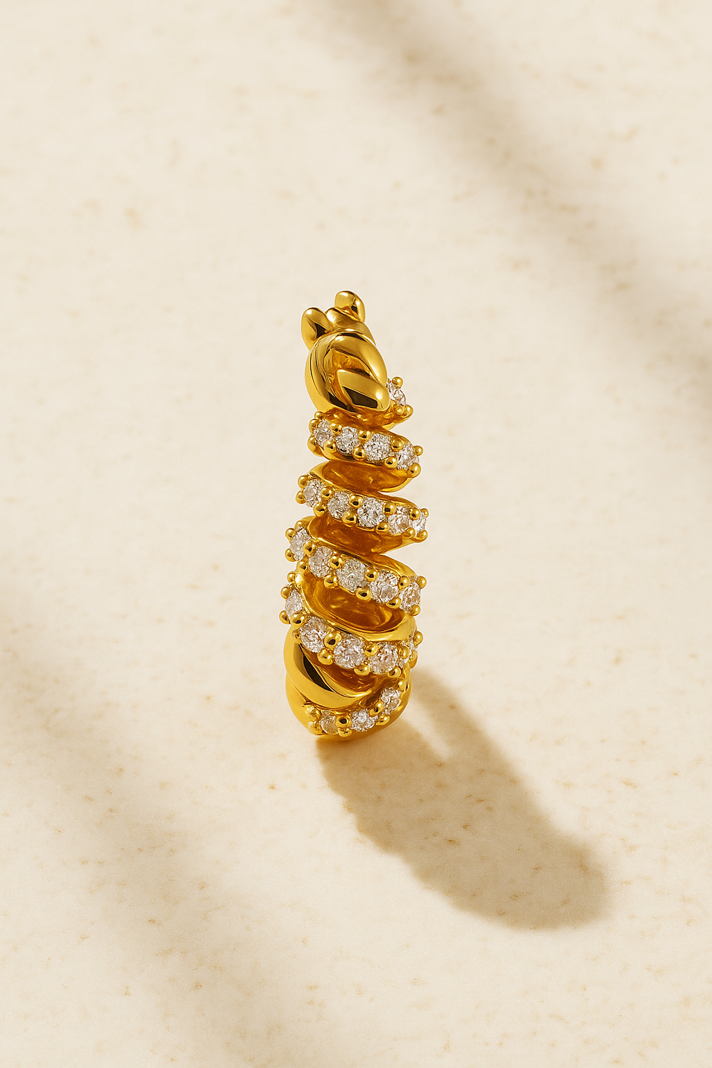 Close-up of Marielle Gold Huggie Earring highlighting the ribbon texture and 18ct gold finish with pavé sparkle.
