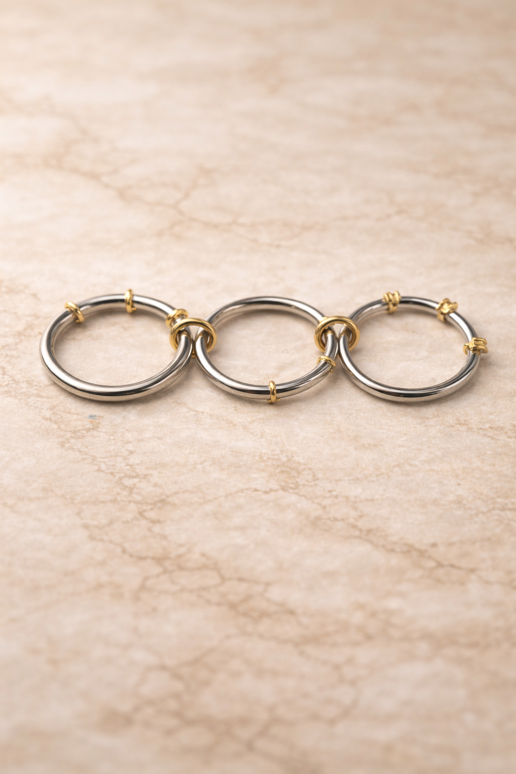 Connected band ring with polished silver loops and gold accents