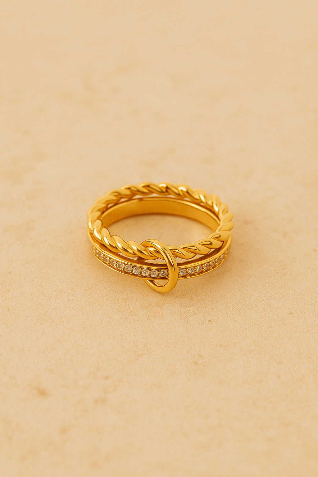 Side view of multiple Livia-style gold rings stacked on fingers with dark burgundy manicure.