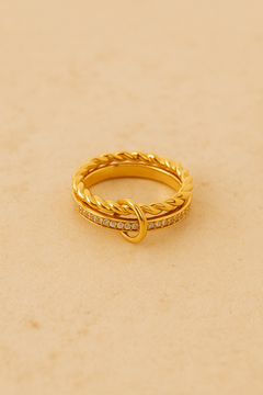 Side view of multiple Livia-style gold rings stacked on fingers with dark burgundy manicure.