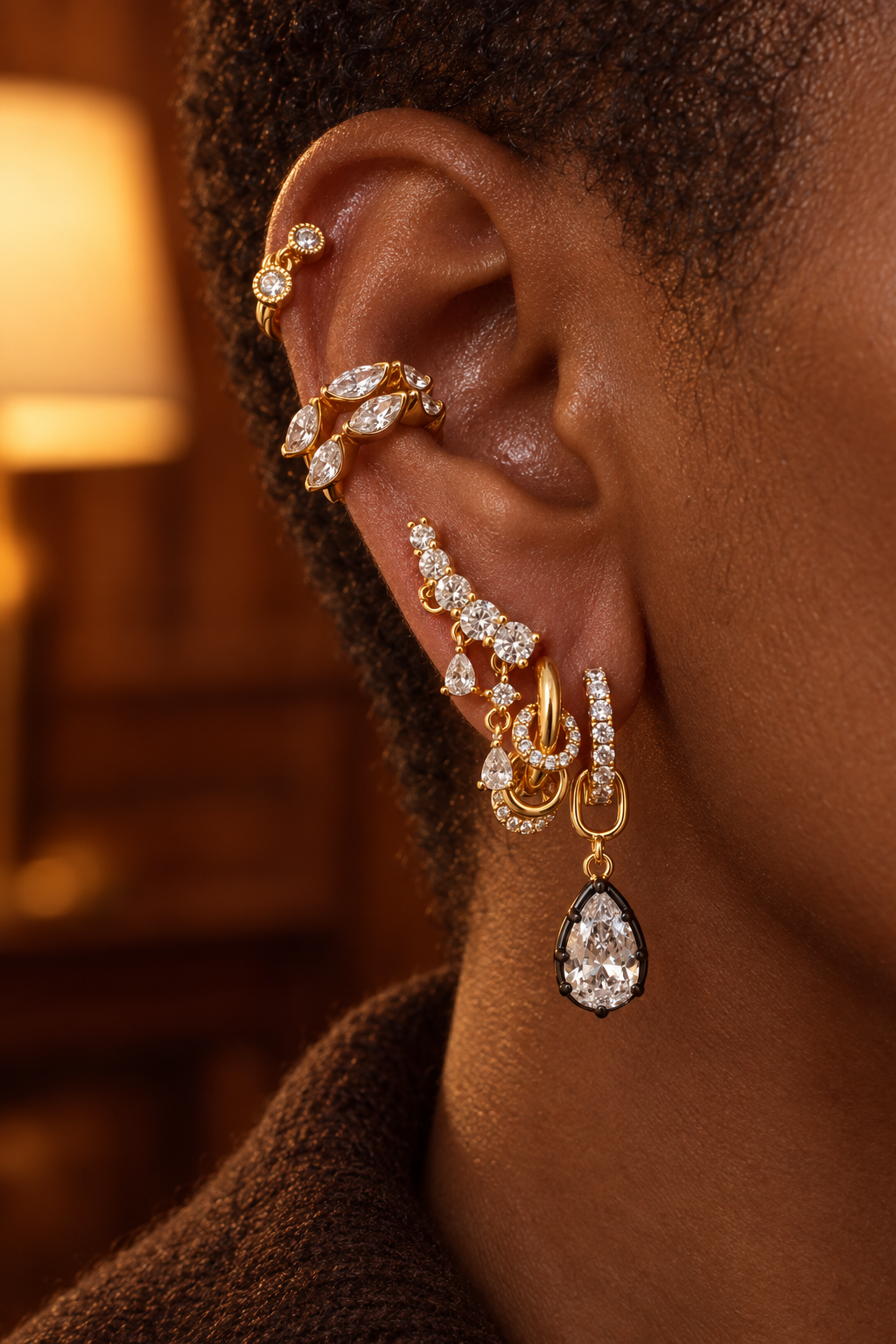 Full gold ear stack by Galleria Armadoro featuring the Simple Eternity Pavé Huggie 8.5 with a black rhodium teardrop charm, layered with cuffs, studs and crystal earrings.