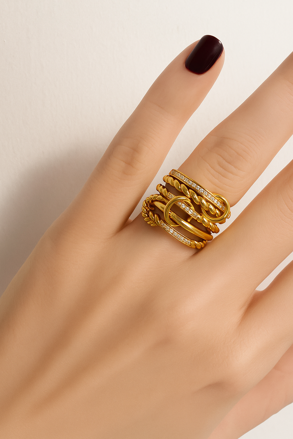 Livia twisted rope and pavé gold ring lying flat on textured beige surface, product detail shot.