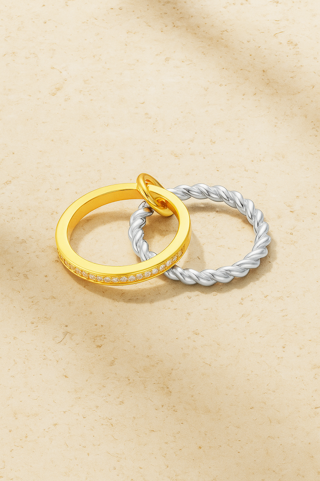 Two-tone Livia ring with silver twisted band and gold pavé bar on warm stone background.