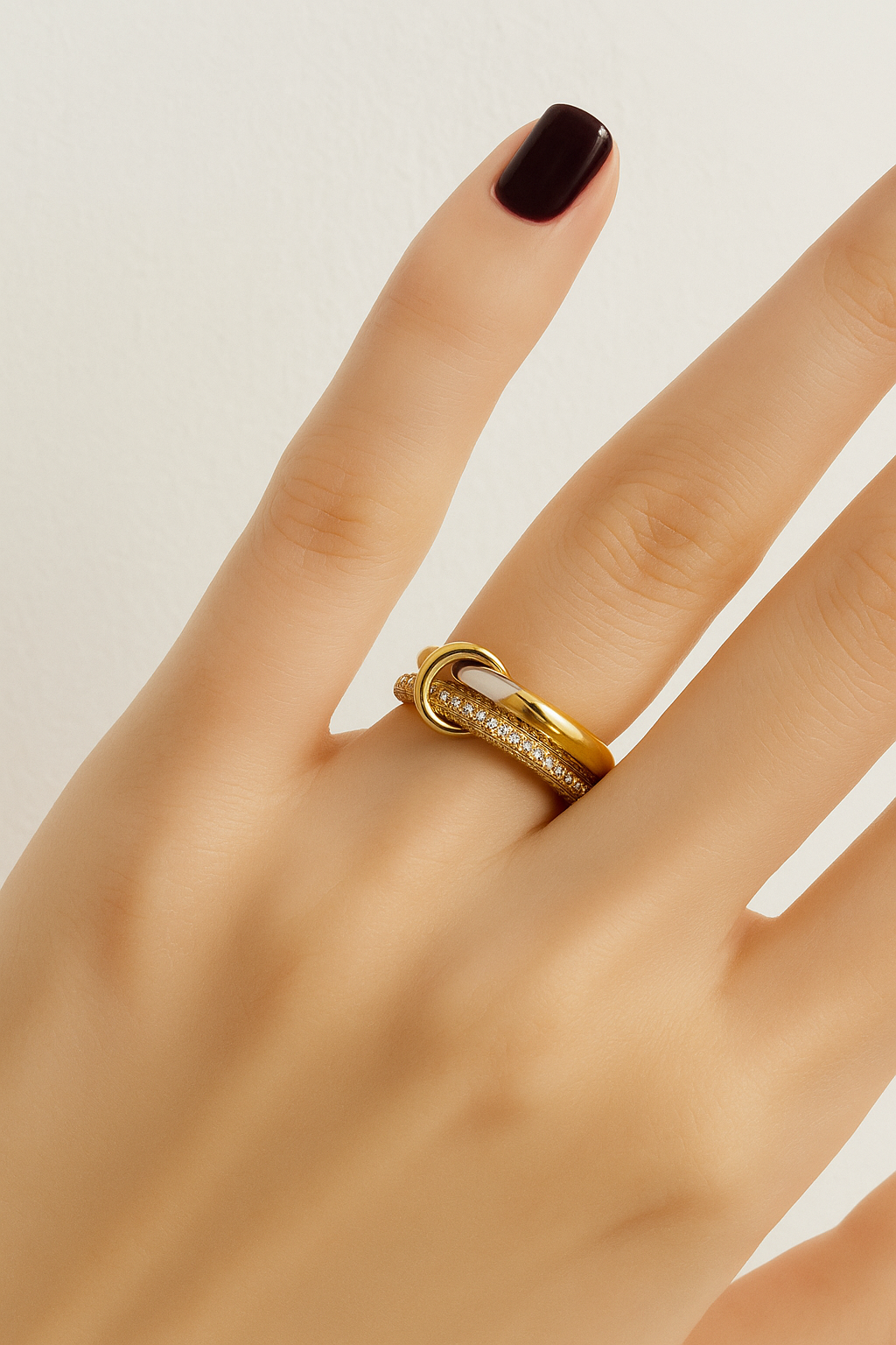 Nora Speira two-tone linked pavé ring worn on finger with deep burgundy manicure.