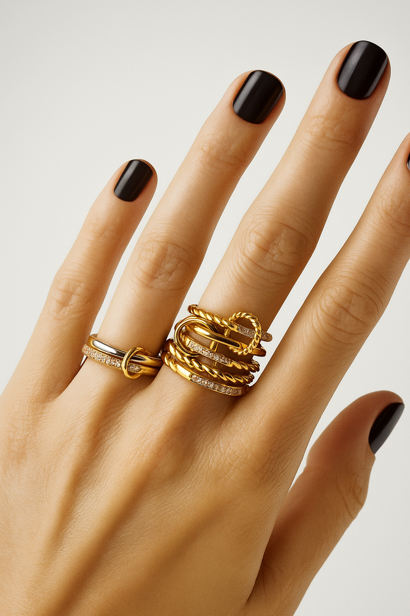 Dark nail polish styling with two-tone Livia ring and layered gold rings.