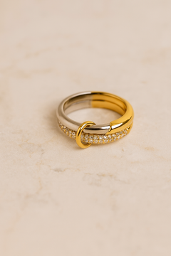 Close-up of Nora Speira ring on marble surface showing half-gold half-silver band and pavé detail.