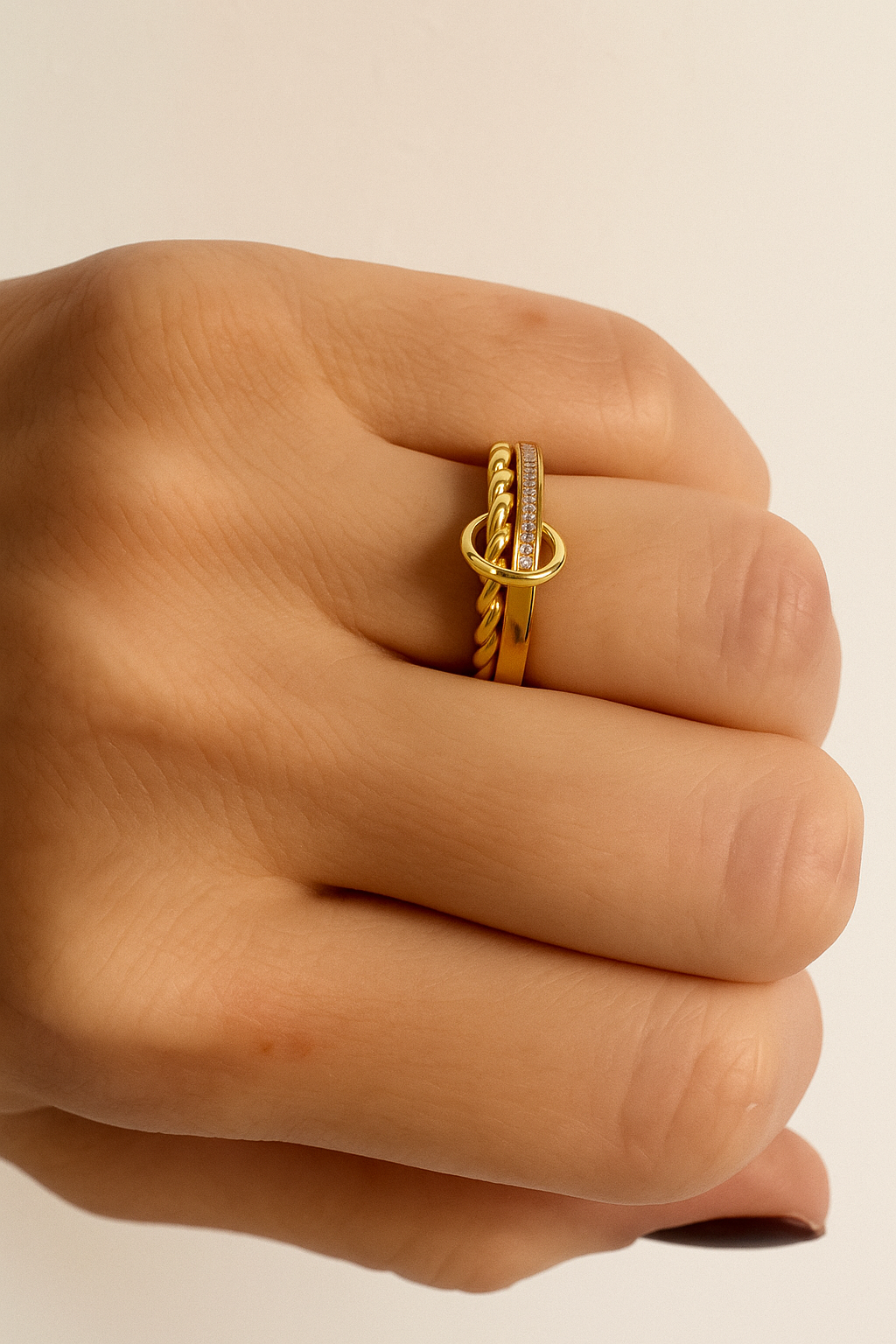 Editorial shot of mixed gold pavé and twisted rings on hand with glossy black nails.