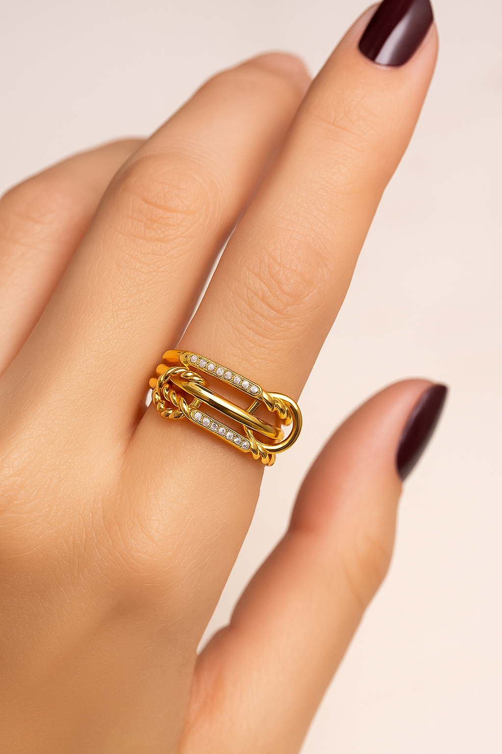 Carmella Speira triple-band architectural ring worn on hand with burgundy nails.