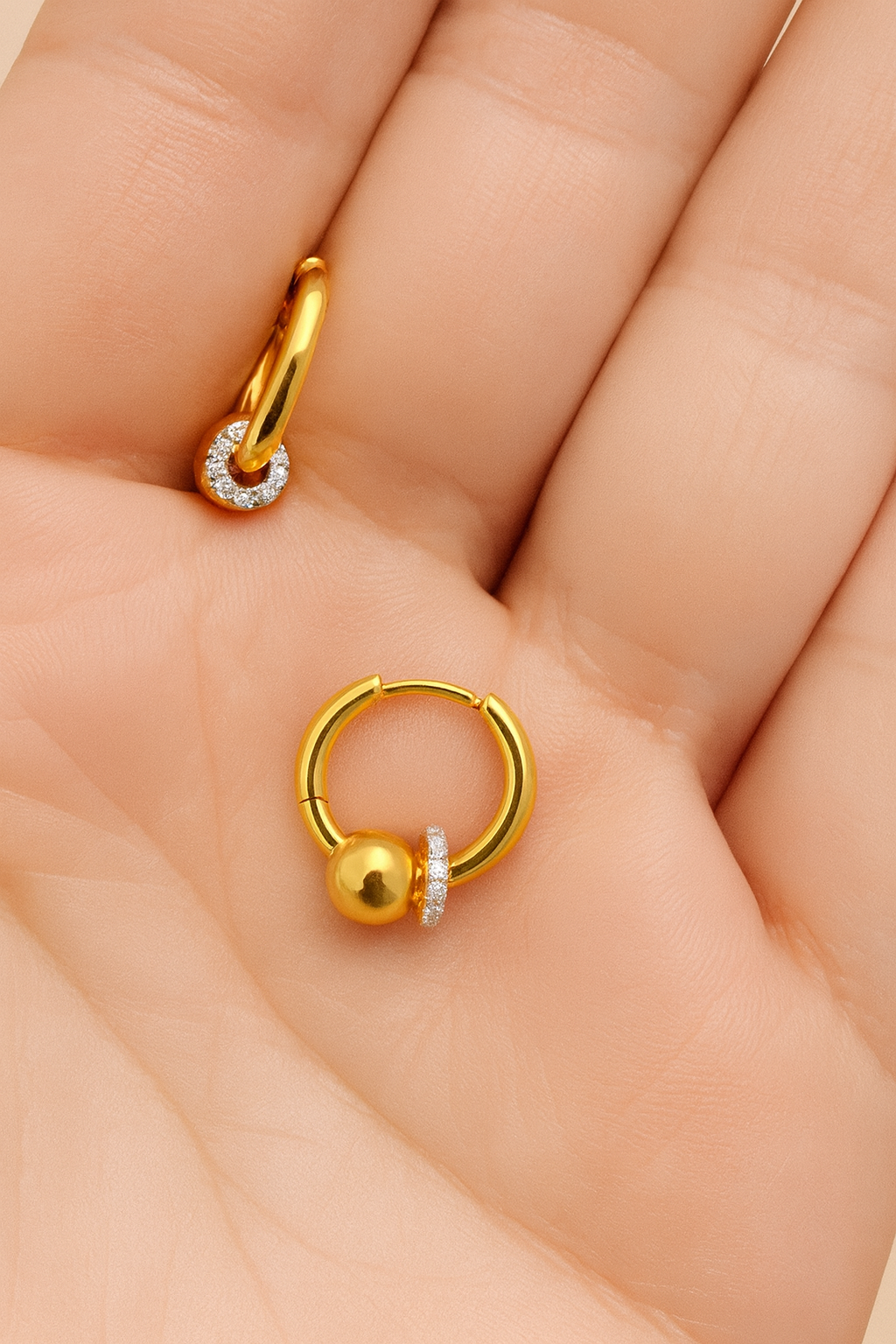 Gold Kora bead huggie earring with full CZ halo resting on palm