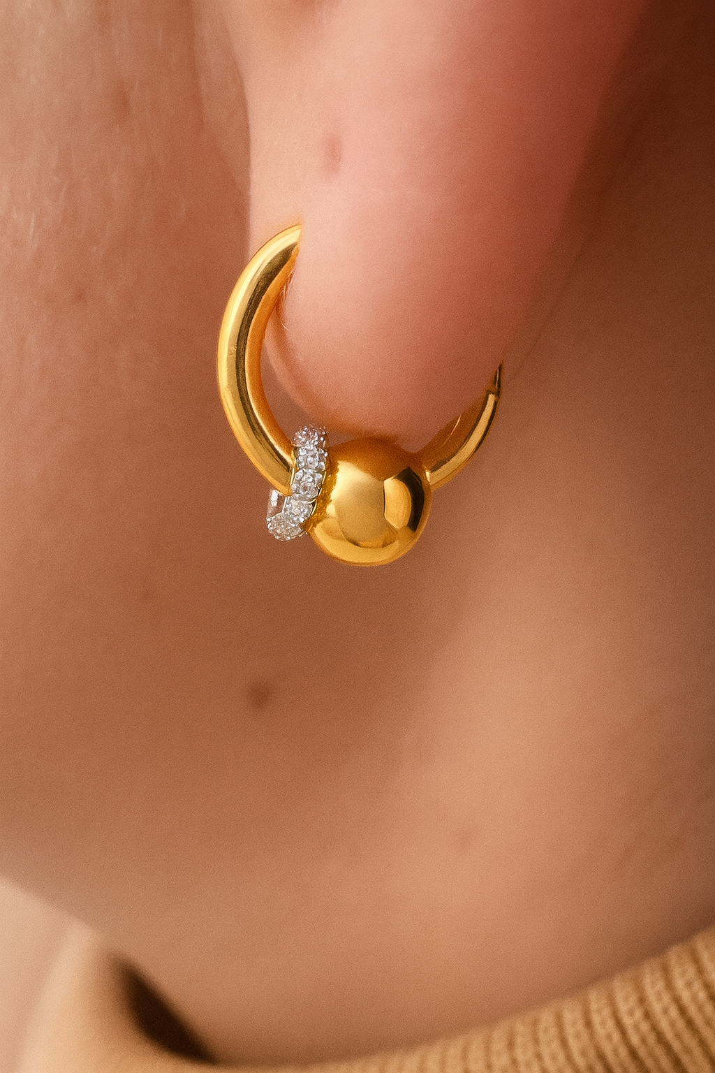 Gold Kora bead huggie worn in lobe piercing with full CZ halo