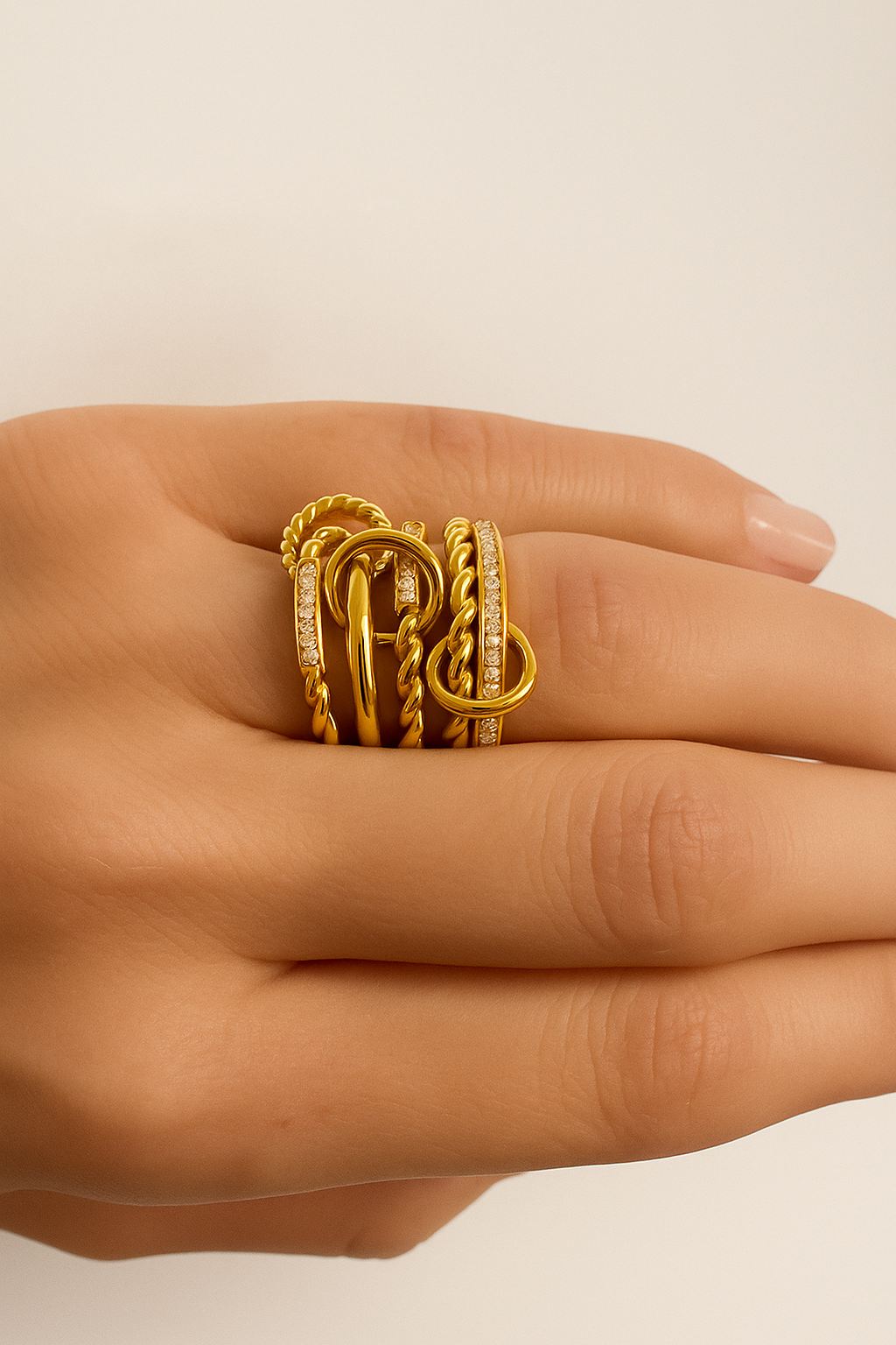 Livia ring components – twisted rope band and pavé circle charm linked together, floating on beige backdrop.