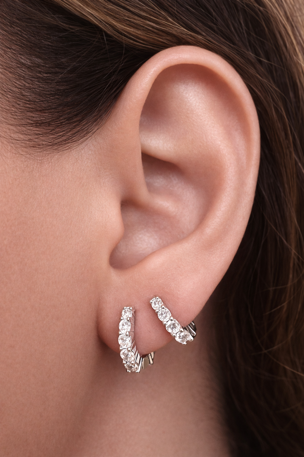 Two earrings in one ear styling with jumbo graduated sterling silver huggies for second ear piercings