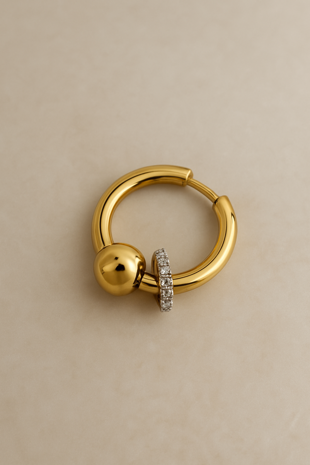 Gold Kora bead huggie worn in lobe piercing with full CZ halo