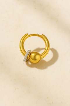 Kora gold piercing bead huggie on matte beige marble background