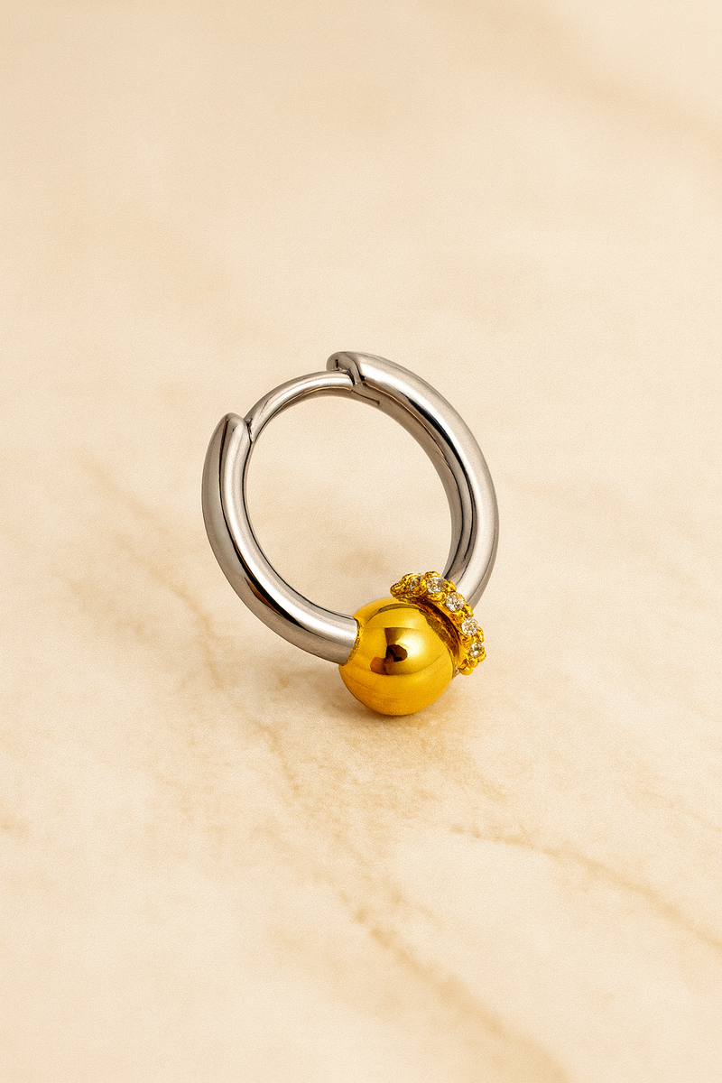 Kora piercing bead huggie earring open to show hinged closure and mixed-metal design