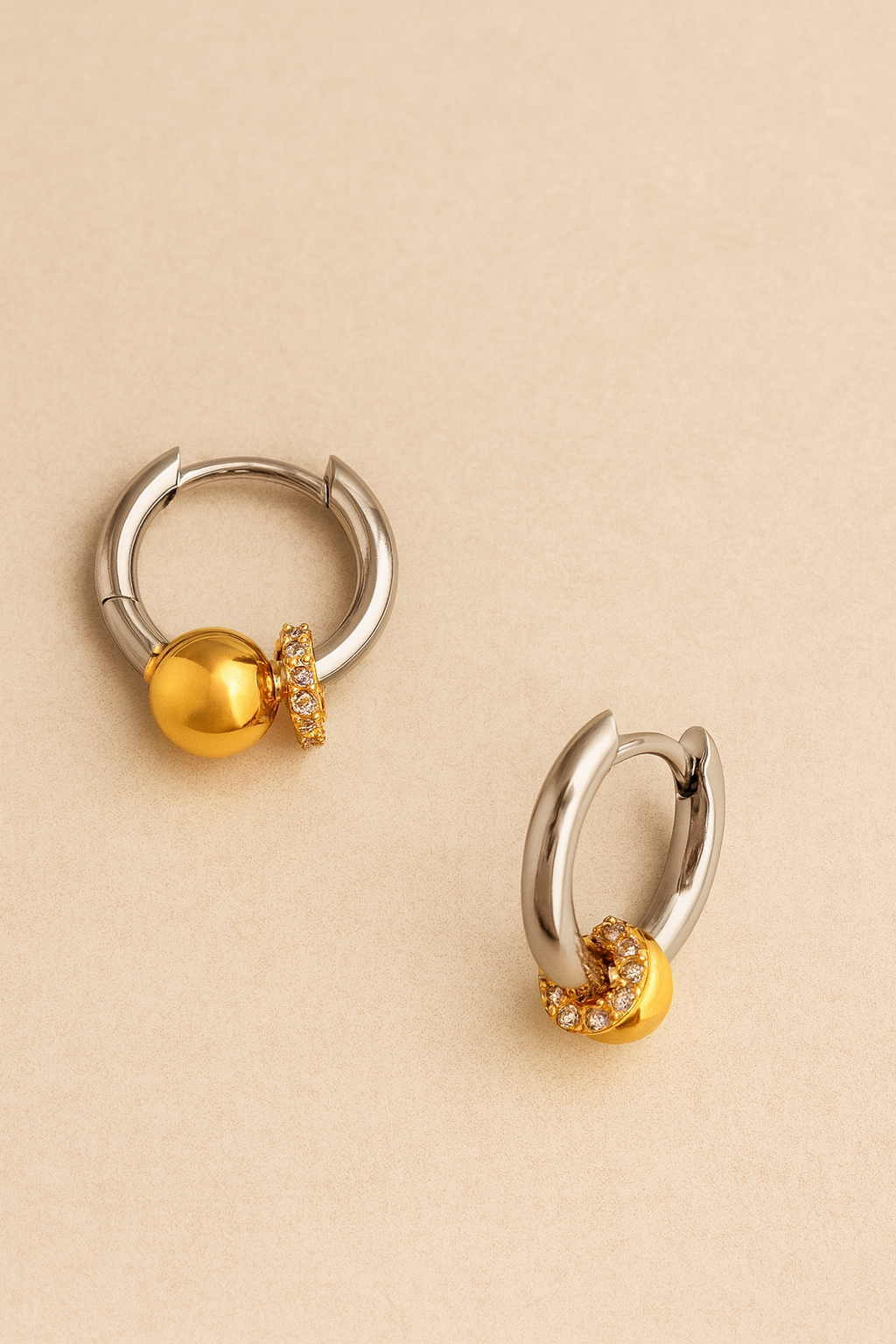 Kora two-tone bead huggie resting on textured stone, highlighting CZ halo and polished silver hoop