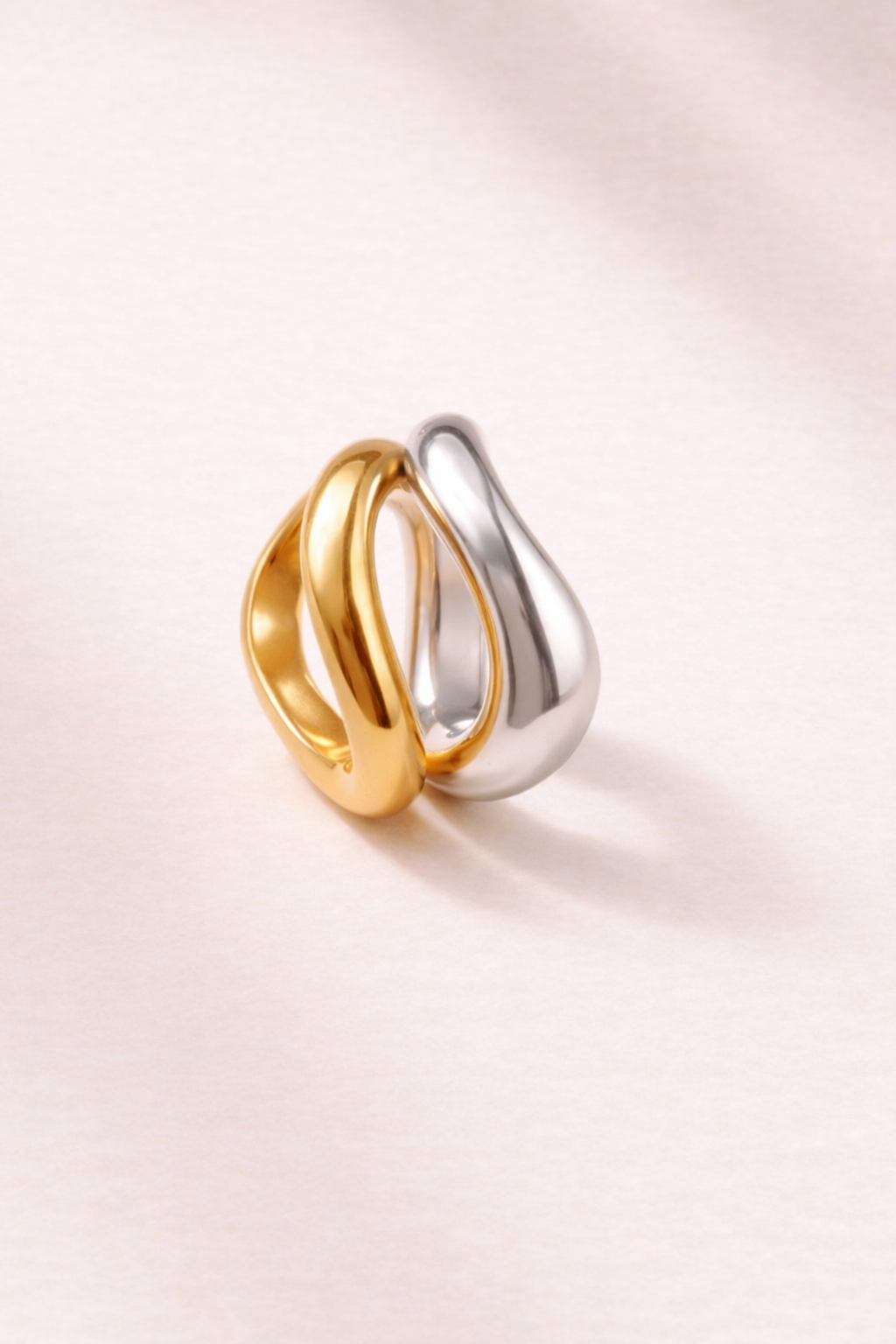 Gold and silver Kyma Vector rings styled side by side on minimal background