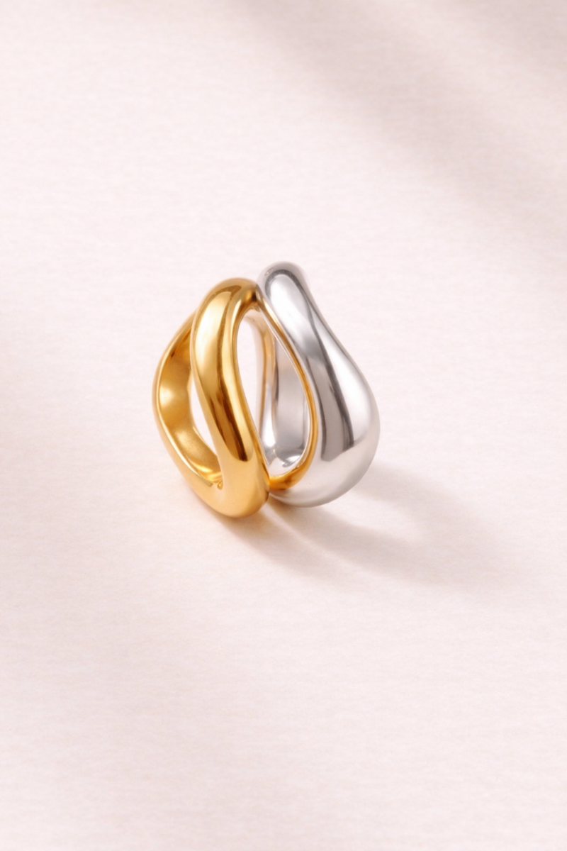 Gold and silver Kyma Vector rings styled side by side on minimal background
