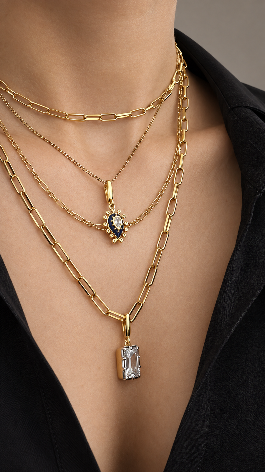 Layered gold and mixed-metal necklace look by Galleria Armadoro combining fine chains, paperclip necklaces, a blue evil eye pendant and crystal charms.