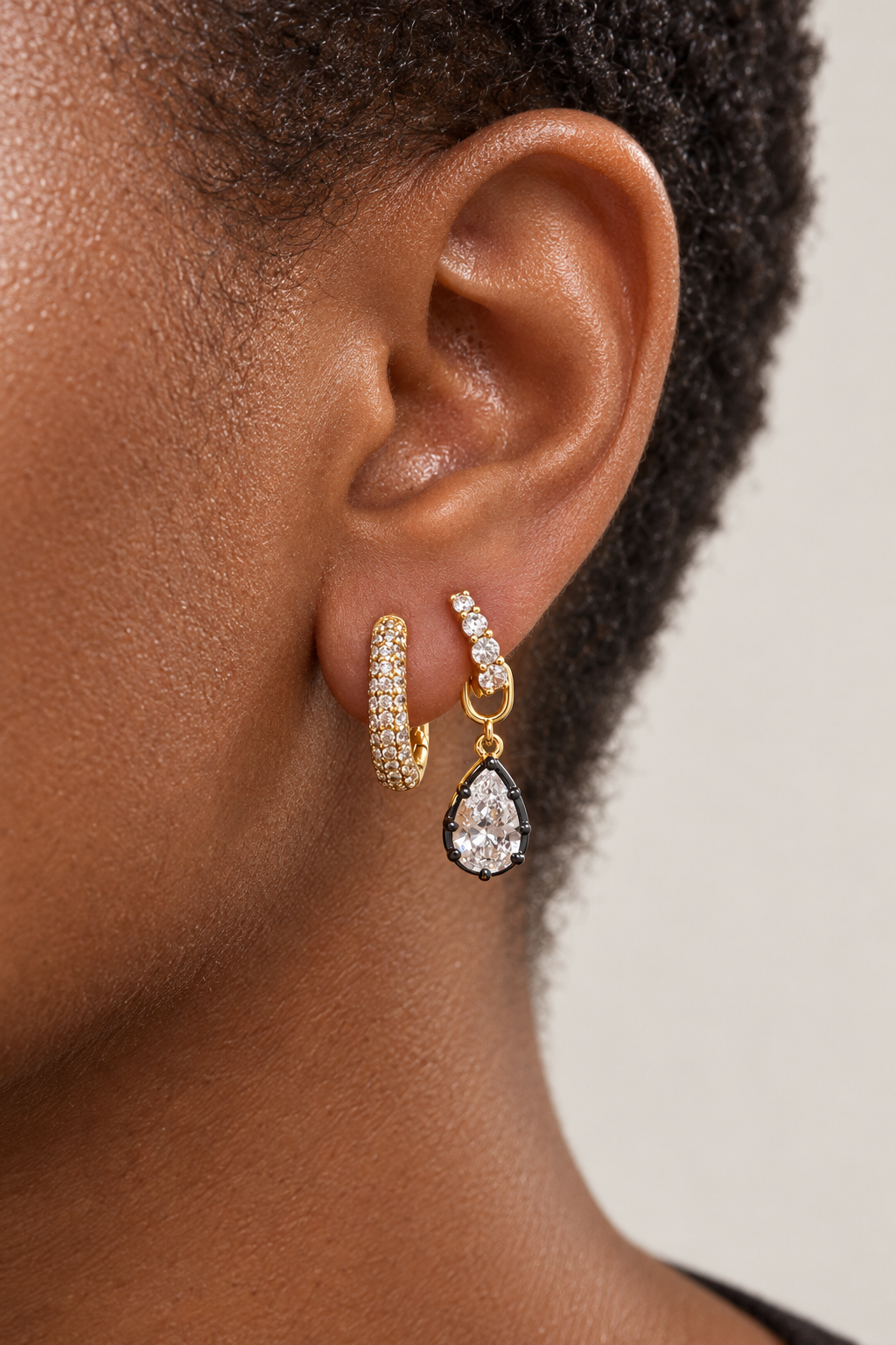 Second ear piercing idea by Galleria Armadoro featuring an all-round pavé oval huggie and the Mini Gala with a black rhodium teardrop charm.