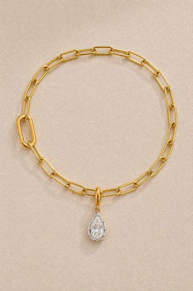Gold paperclip bracelet with mixed-metal Vittoria crystal charm on beige studio background
