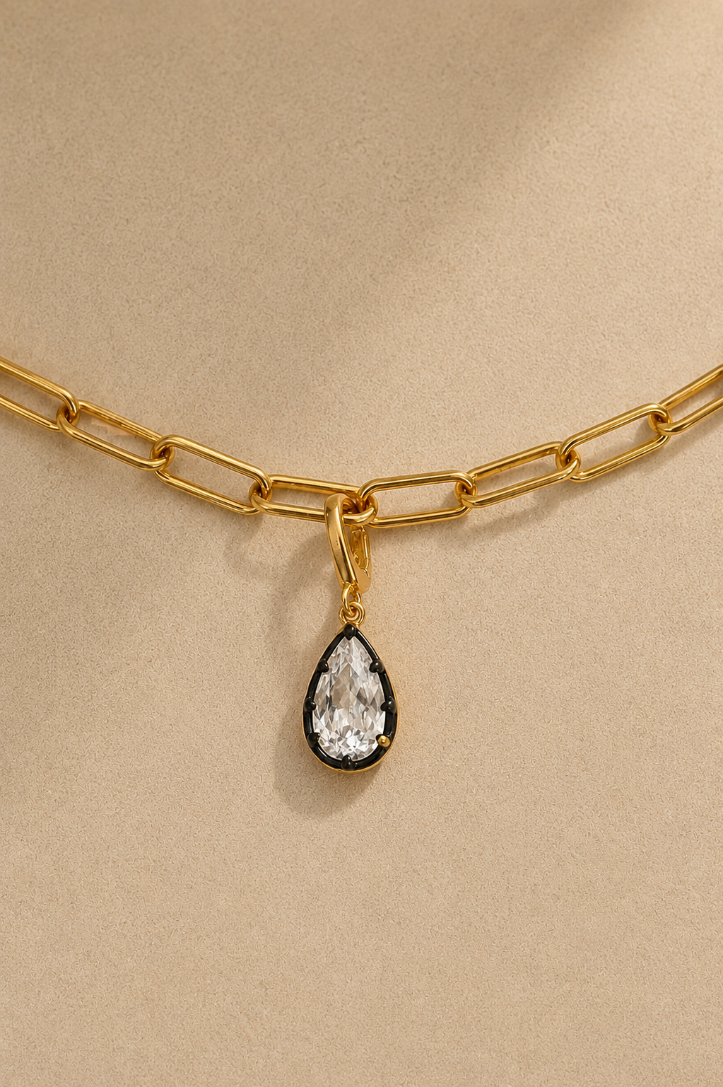 Gold paperclip bracelet with Vittoria black rhodium crystal charm on beige studio background
